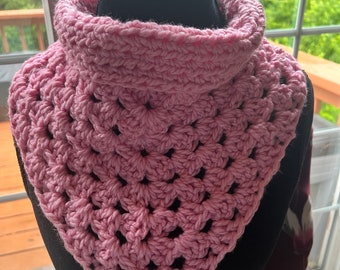 May include: A pink crocheted cowl with a square stitch pattern. The cowl is displayed on a black mannequin.