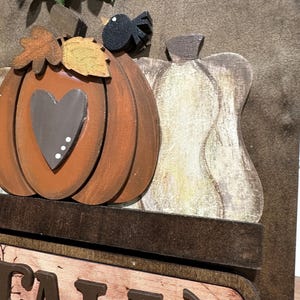 May include: Wooden autumn sign featuring a brown pumpkin, a white gourd, and a black bird. The sign reads "FALL" in brown letters with a green leaf design.