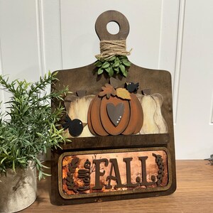 May include: Wooden autumn sign featuring a pumpkin, leaves, and birds. The sign reads "Fall" and has a rustic brown finish.