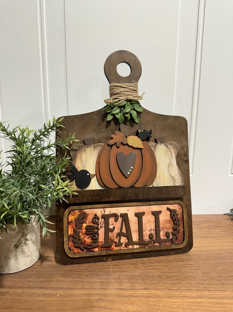 May include: Wooden autumn sign featuring a pumpkin, leaves, and birds. The sign reads "Fall" and has a rustic brown finish.