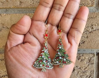 May include: A pair of gold-tone Christmas tree earrings with red stars, green enamel, white pearls, and clear rhinestones.