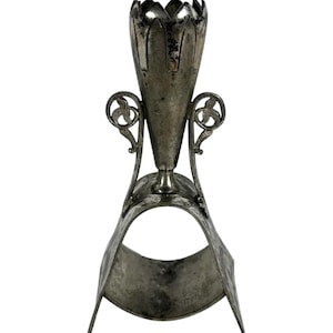 May include: A silver-toned metal vase with a decorative floral design and a curved base. The vase is designed to hold a single flower or stem.