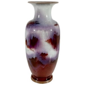 May include: A tall, decorative vase with a flared rim and a rounded body. The vase features a glossy finish with a blend of colors, including shades of purple, white, and deep red. The base and rim have a gold-colored trim.