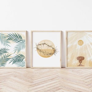 May include: Three framed prints with a religious theme. The first print features a pattern of green palm leaves on a white background. The second print features a brown crown of thorns on a yellow circle. The third print features a brown chalice with a yellow sun and rays of light behind it.
