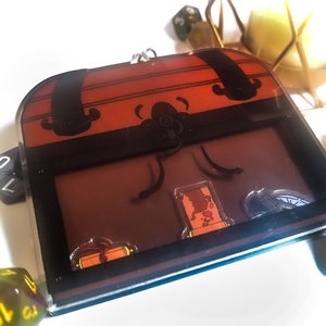 Puede incluir: Un cofre del tesoro de madera marrón con un cierre y bisagras de metal. El cofre está abierto y contiene un mapa enrollado, una brújula y un rollo.