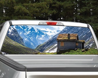 Könnte beinhalten: Ein LKW-Fensteraufkleber mit einer malerischen Berglandschaft und einer kleinen Holzhütte im Vordergrund. Die Berge sind schneebedeckt und der Himmel ist blau.