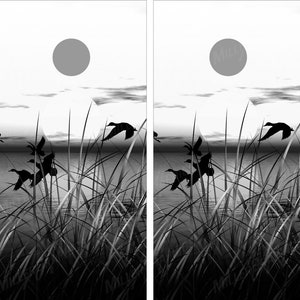 Può includere: Illustrazione in bianco e nero di un tramonto sul lago con erba alta e anatre in volo. Il sole è un grande cerchio nel cielo.