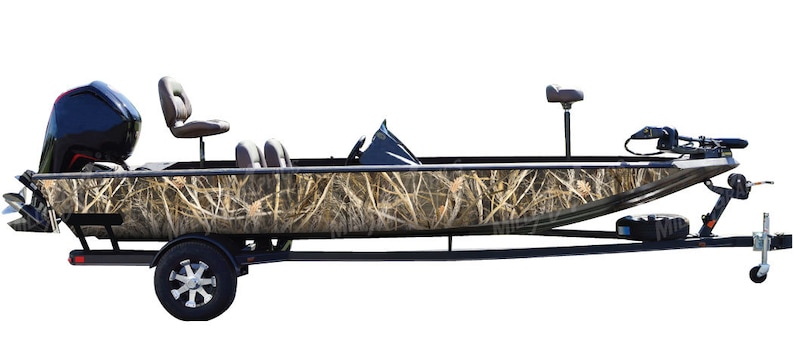Puede incluir: Un barco de pesca de camuflaje negro y marr&oacute;n con un remolque. El barco tiene dos asientos y un motor.