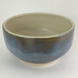 May include: A ceramic bowl with a light grey interior and a blue and brown glaze on the exterior.