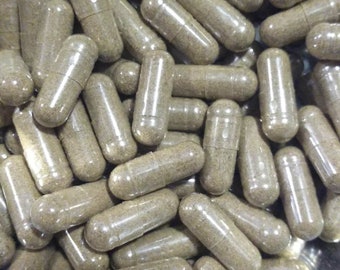 May include: A close-up shot of numerous clear capsules filled with a light brown powder. The capsules are oval-shaped and appear to be filled with a herbal supplement. The capsules are in a metal bowl.