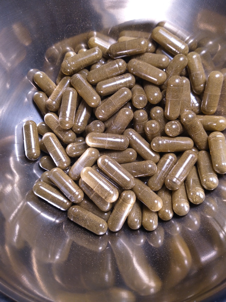 May include: A metal bowl filled with a large quantity of brown capsules. The capsules are translucent and filled with a brown powder.