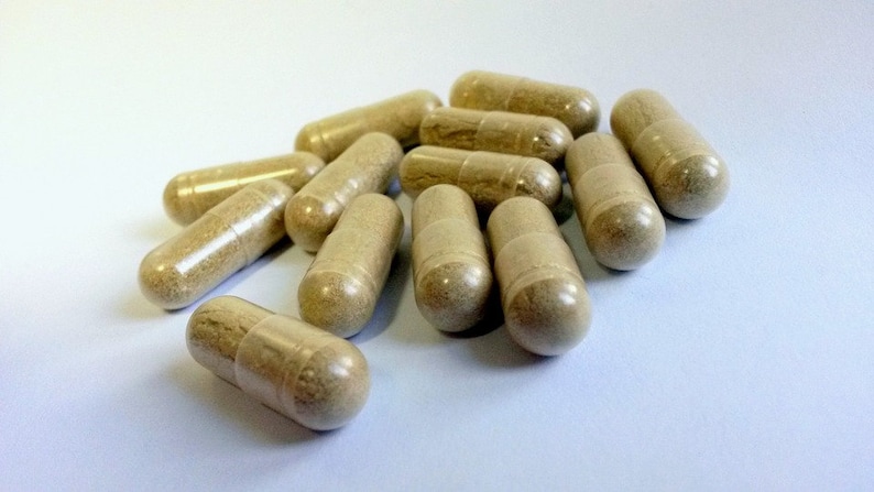 May include: A pile of beige capsules on a white surface.