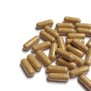 May include: A large pile of brown capsules on a white background. The capsules are all the same size and shape, and they are arranged in a random pattern.