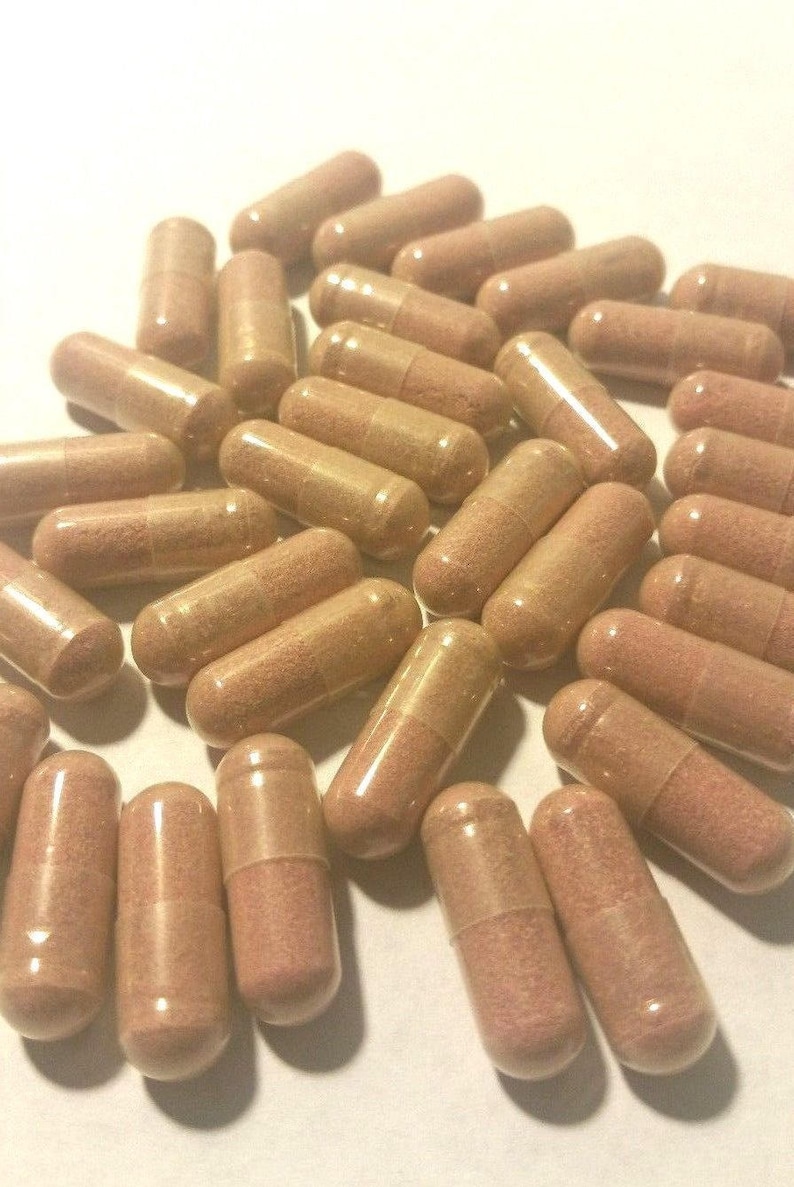 May include: A large group of brown capsules, likely dietary supplements, are scattered on a white surface.