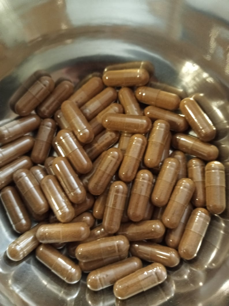 Op de afbeelding: Een close-up van een kom vol bruine capsules. De capsules zijn gemaakt van een helder materiaal en bevatten een bruin poeder.