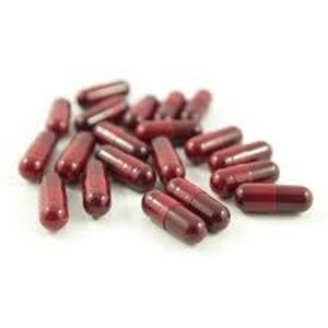 May include: A pile of dark red capsules on a white surface.