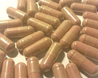 May include: A collection of light brown capsules, each with a translucent, segmented shell. The capsules are filled with a reddish-brown powder, and are scattered across a white surface. The image is well-lit, highlighting the texture and color of the capsules.