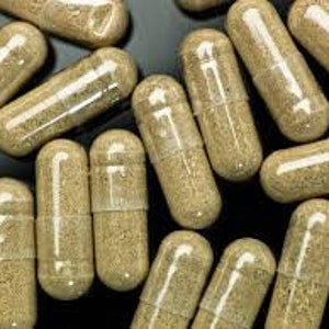 May include: A close-up of a group of clear capsules filled with a light brown powder.