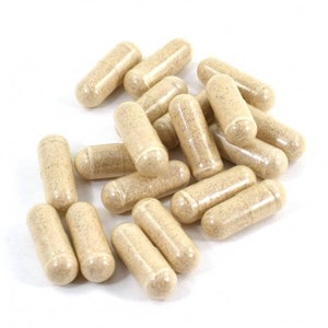 May include: A pile of beige capsules on a white background. The capsules are all the same size and shape, and they are arranged in a random pattern.