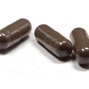 May include: Three brown capsules on a white surface.