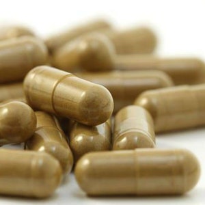 May include: A close-up of a pile of brown capsules. The capsules are arranged in a random pattern and are all the same size and shape.
