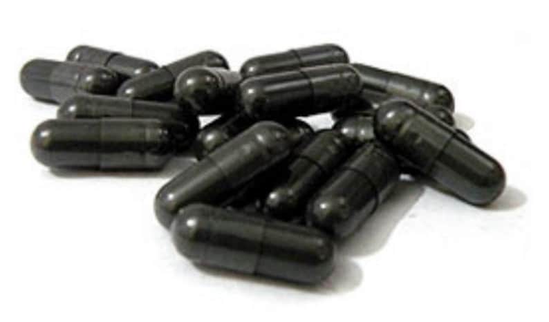 May include: A pile of black capsules, likely dietary supplements, are scattered on a white surface.
