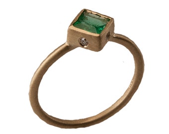 May include: A gold ring with a square emerald gemstone and a small diamond accent.