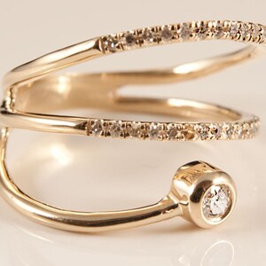 May include: A gold ring with three bands, each set with small diamonds. The top band has a larger, round diamond at the end.