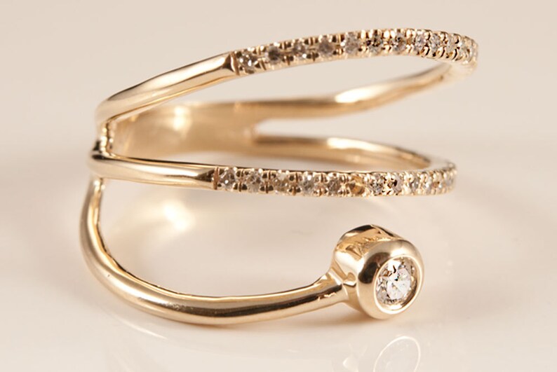 May include: A gold ring with three bands, each set with small diamonds. The top band has a larger, round diamond at the end.