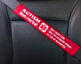 May include: Red car seat belt cover with the text "AUTISM Non-verbal" and a medical symbol. The text below reads "May resist help. May not recognize danger. At risk of wandering."