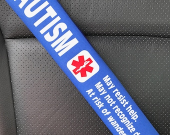 Könnte beinhalten: Blauer Sicherheitsgurtbezug mit dem Wort "AUTISMUS" und einem roten medizinischen Symbol. Der Text lautet "Kann Hilfe verweigern. Kann Gefahren nicht erkennen. Gefahr des Umherwanderns."