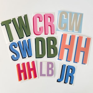 May include: A set of colorful, personalized initial stickers with a variety of fonts and styles. The stickers feature the letters TW, CR, CW, SW, DB, HH, LB, and JR.