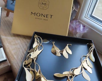 Collar y pendientes Monet de cuatro hilos con diseño de hojas estilizadas en tono dorado, en su caja original.