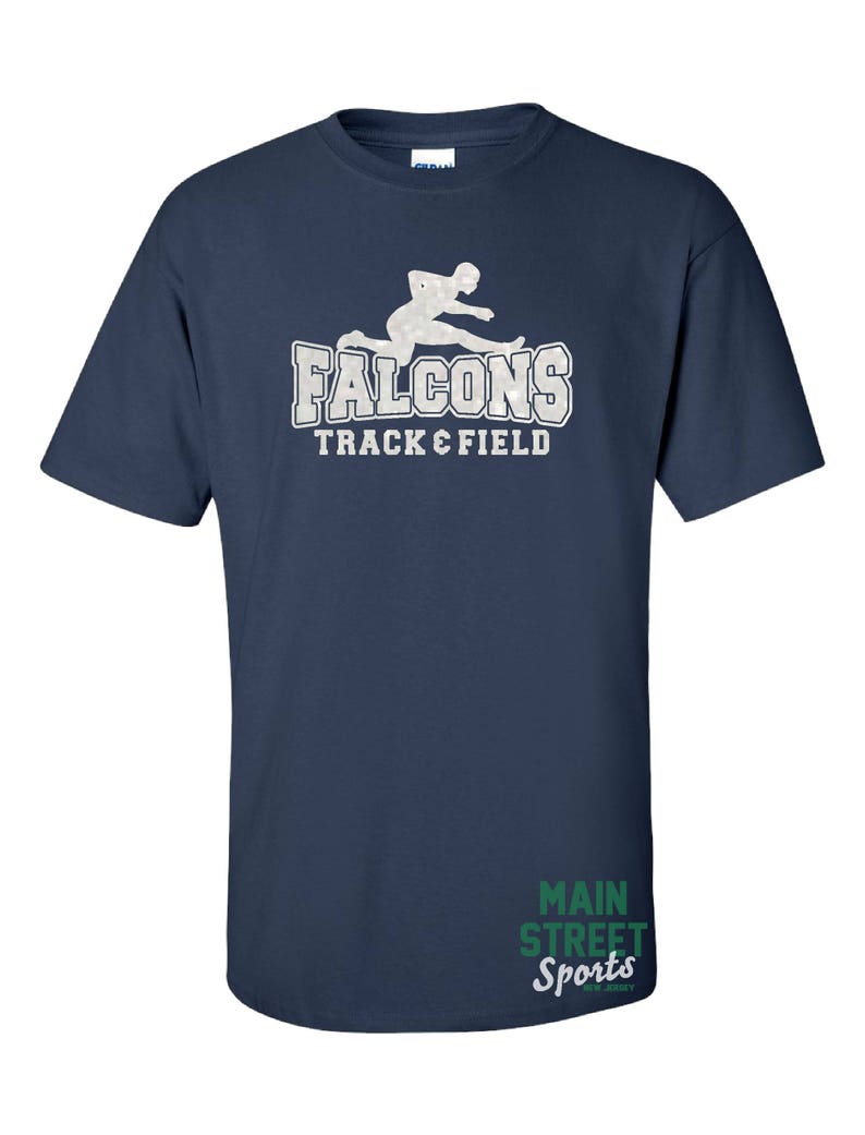 Op de afbeelding: Donkerblauw T-shirt met een wit silhouet van een hardloper en de tekst "Falcons Track & Field". De rechteronderhoek van het shirt heeft de tekst "Main Street Sports" in groen.