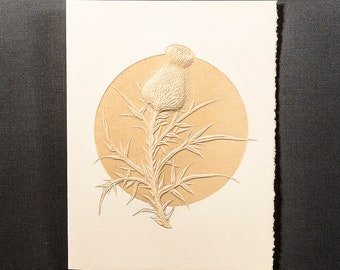 May include: A white paper card with a beige circle in the center. The circle features a detailed embossed image of a thistle flower.