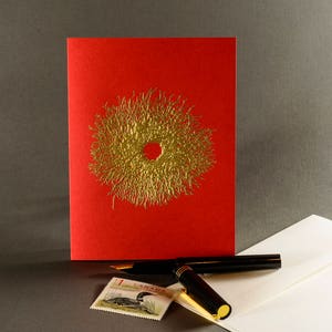 Puede incluir: Una tarjeta roja con un dise&ntilde;o de corona en l&aacute;mina dorada. La tarjeta est&aacute; sobre un sobre blanco con un bol&iacute;grafo negro y un sello con un pato.