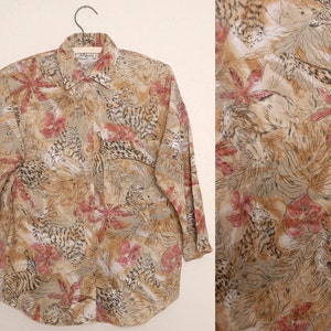 May include: A long-sleeved button-up shirt with a brown and beige background. The shirt features a repeating pattern of red flowers, brown leaves, and black and white animal print.