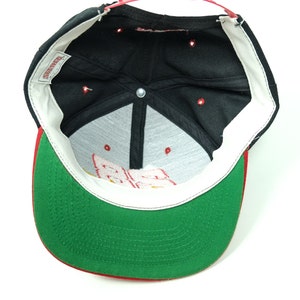 Peut inclure: Casquette de baseball noire et verte avec une visi&egrave;re rouge. L'int&eacute;rieur de la casquette est noir avec une &eacute;tiquette blanche qui dit "Starter".