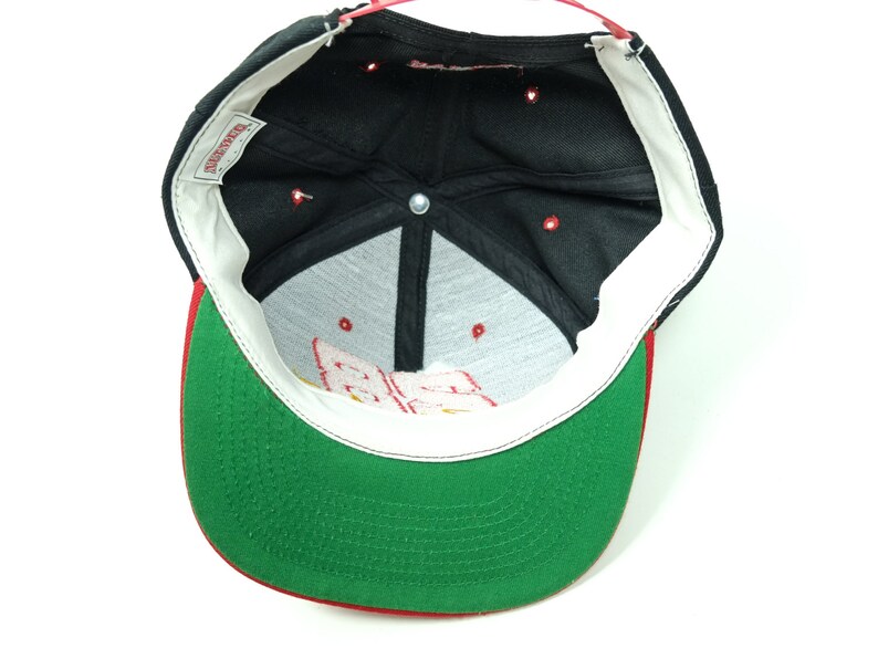 Peut inclure: Casquette de baseball noire et verte avec une visi&egrave;re rouge. L'int&eacute;rieur de la casquette est noir avec une &eacute;tiquette blanche qui dit "Starter".