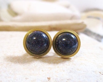 May include: A pair of gold stud earrings with a dark blue, sparkly stone in each setting.