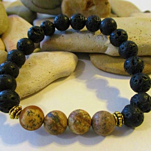 May include: A black lava rock and brown jasper beaded bracelet with gold spacers. The bracelet is made with 8mm beads and is approximately 7 inches in length.