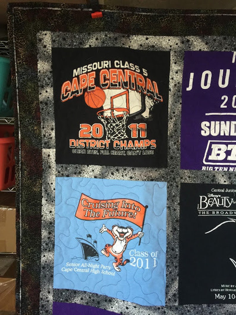 May include: A quilt with different fabric squares. The top left square is a black and white basketball jersey with the text "Missouri Class 5 Cape Central 2011 District Champs Clear Eyes, Full Heart, Can't Lose". The top right square is a purple jersey with the text "Jour 20 Sund BT Big Ten Ne". The bottom left square is a blue jersey with a cartoon tiger and the text "Cruising Into The Future! Class of 2011 Senior All-Night Party Cape Central High School". The bottom right square is a black jersey with the text "Central Junior Beauty The Broadway Music by A Lyrics by Howard May 10-".