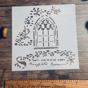 May include: A white stencil featuring a gothic window design with floral accents and script text. A wooden ruler with centimeter markings and the text "The Order of the Planner Stencils" is visible. A makeup brush is also in the image.