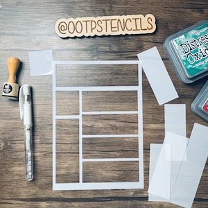 Peut inclure: Un pochoir blanc avec une grille de six découpes rectangulaires, un tampon en bois, un stylo blanc et une feuille de plastique transparente. Le pochoir est sur une surface en bois. Le pochoir est étiqueté "@OOTPSTENCILS".