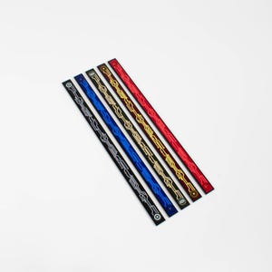 Puede incluir: Cinco cintas de adorno de diferentes colores con un patrón geométrico. Las cintas están dispuestas en forma de abanico de izquierda a derecha: plata, azul, negro, oro y rojo.