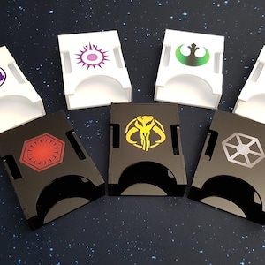Peut inclure: Six plateaux à dés différents avec divers symboles de faction Star Wars. Les plateaux sont en acrylique noir et blanc. Les symboles incluent l'Alliance Rebelle, l'Empire Galactique, le Premier Ordre, le Mandalorien, les Sith et la République.