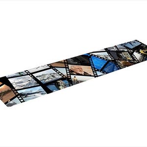 Peut inclure: Une nappe rectangulaire avec un motif de bande de film, affichant diverses images de paysages et d'architecture. La nappe est principalement noire, avec un motif répétitif de cadres de film, présentant un collage de photographies.