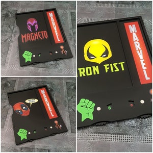 May include: Two black and red Marvel themed game trays with a green fist, a red and black character, and the text "MARVEL" and "MAGNETO".