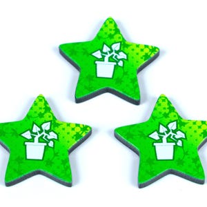 Può includere: Tre gettoni di legno a forma di stella verde con un'icona di pianta in vaso bianca. Le stelle hanno un bordo verde scuro e uno sfondo verde chiaro con un motivo a foglie. I gettoni sono disposti su uno sfondo bianco.