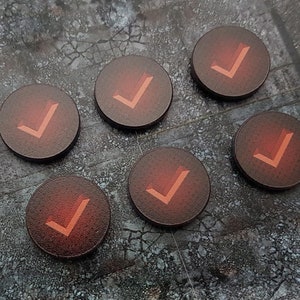 May include: Six red round tokens with a white tick symbol on each. The tokens are on a grey textured surface.